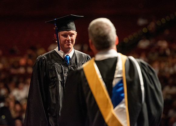 Students partipate in walking to graduate from the College of Business and Communication.
