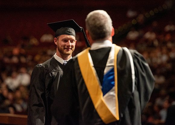 Students partipate in walking to graduate from the College of Business and Communication.
