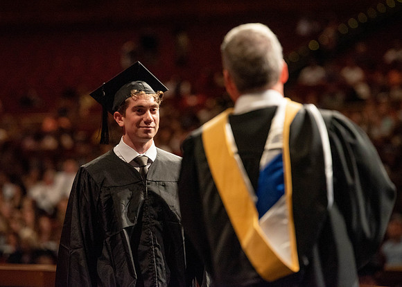 Students partipate in walking to graduate from the College of Business and Communication.