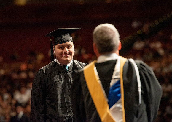 Students partipate in walking to graduate from the College of Business and Communication.