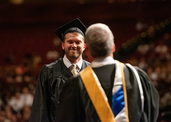 Students partipate in walking to graduate from the College of Business and Communication.