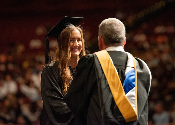 Students partipate in walking to graduate from the College of Business and Communication.