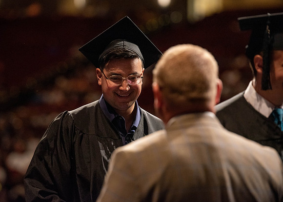 Students partipate in walking to graduate from the College of Business and Communication.