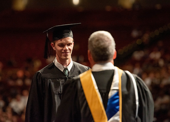 Students partipate in walking to graduate from the College of Business and Communication.
