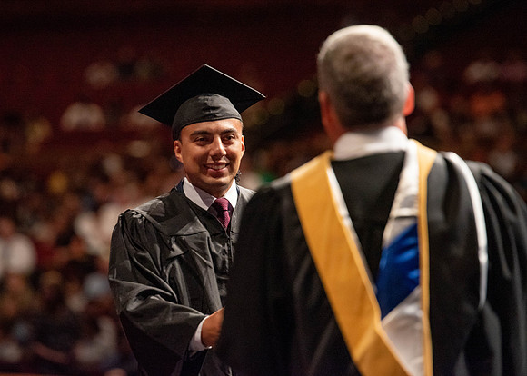 Students partipate in walking to graduate from the College of Business and Communication.