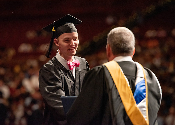 Students partipate in walking to graduate from the College of Business and Communication.