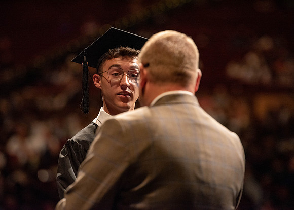 Students partipate in walking to graduate from the College of Business and Communication.