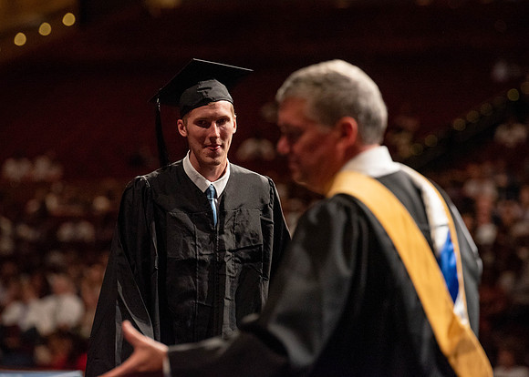 Students partipate in walking to graduate from the College of Business and Communication.