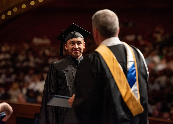 Students partipate in walking to graduate from the College of Business and Communication.