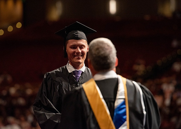 Students partipate in walking to graduate from the College of Business and Communication.