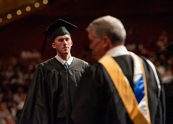 Students partipate in walking to graduate from the College of Business and Communication.