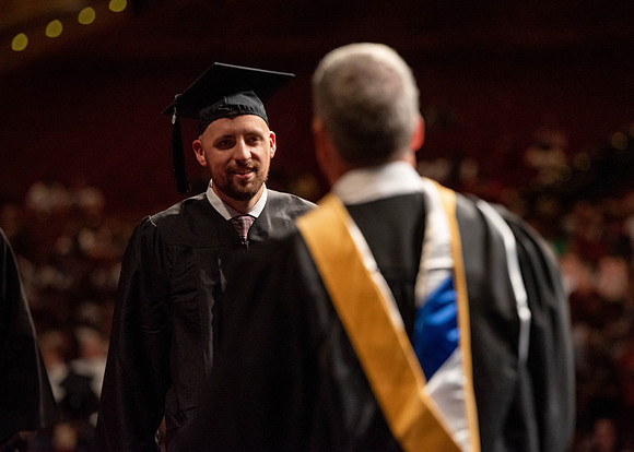 Students partipate in walking to graduate from the College of Business and Communication.