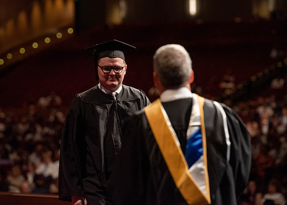 Students partipate in walking to graduate from the College of Business and Communication.