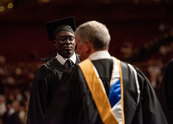 Students partipate in walking to graduate from the College of Business and Communication.