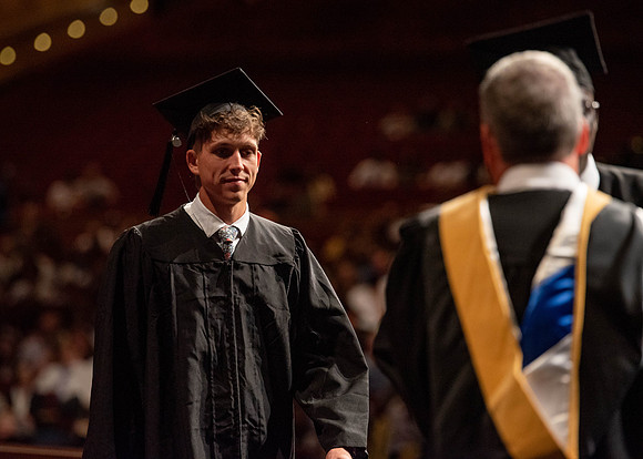Students partipate in walking to graduate from the College of Business and Communication.