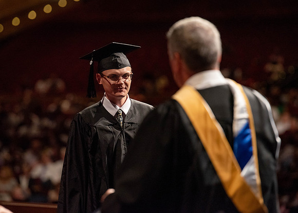 Students partipate in walking to graduate from the College of Business and Communication.