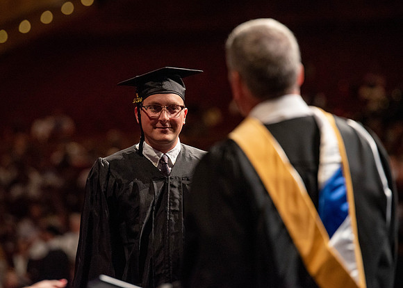 Students partipate in walking to graduate from the College of Business and Communication.