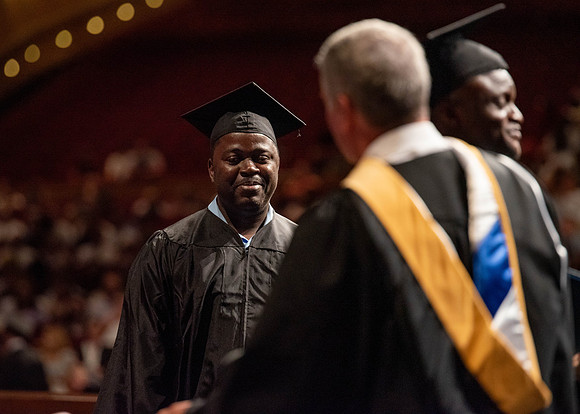 Students partipate in walking to graduate from the College of Business and Communication.