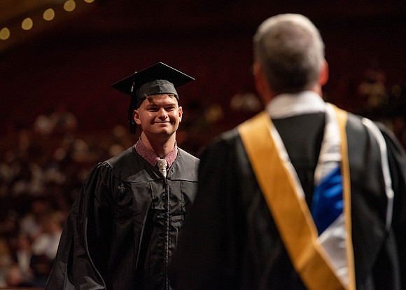Students partipate in walking to graduate from the College of Business and Communication.