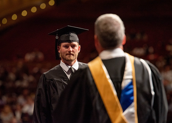 Students partipate in walking to graduate from the College of Business and Communication.
