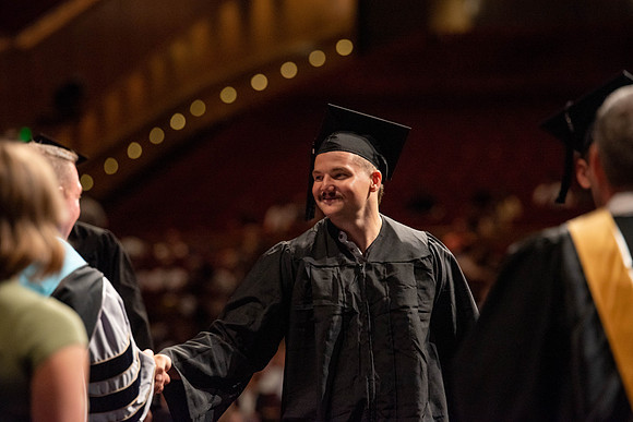 Students partipate in walking to graduate from the College of Business and Communication.