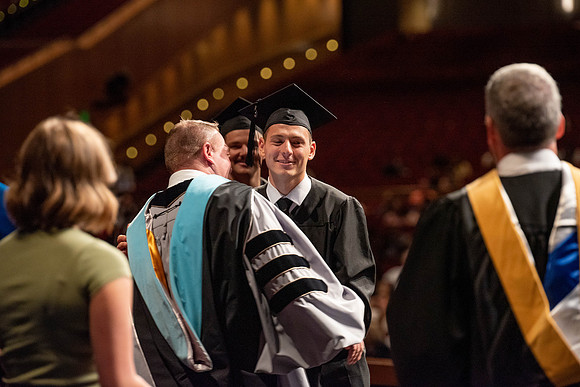 Students partipate in walking to graduate from the College of Business and Communication.