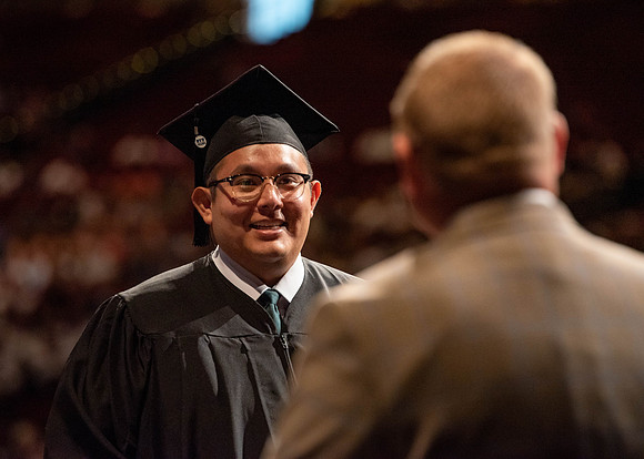 Students partipate in walking to graduate from the College of Business and Communication.