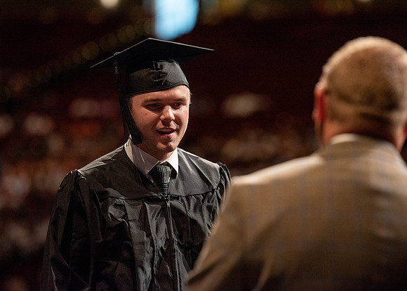 Students partipate in walking to graduate from the College of Business and Communication.