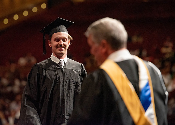 Students partipate in walking to graduate from the College of Business and Communication.