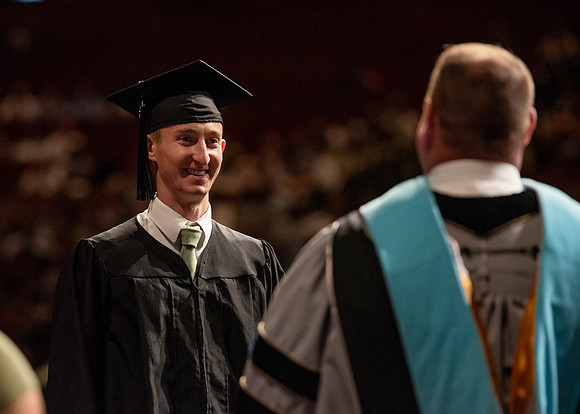 Students partipate in walking to graduate from the College of Business and Communication.