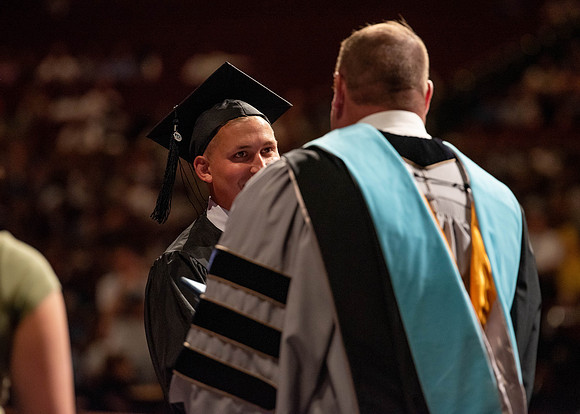 Students partipate in walking to graduate from the College of Business and Communication.