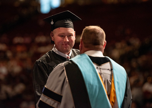 Students partipate in walking to graduate from the College of Business and Communication.