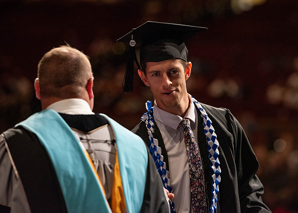 Students partipate in walking to graduate from the College of Business and Communication.