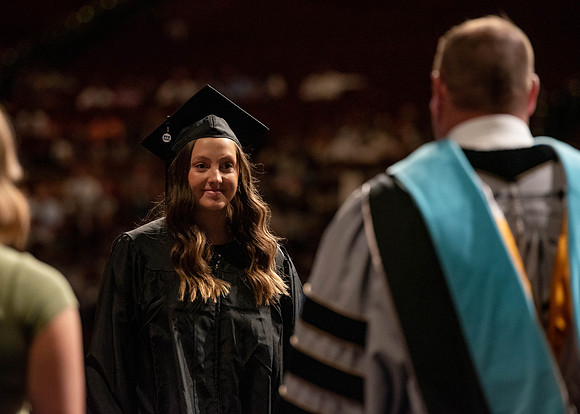 Students partipate in walking to graduate from the College of Business and Communication.
