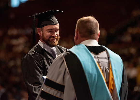 Students partipate in walking to graduate from the College of Business and Communication.