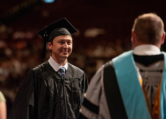 Students partipate in walking to graduate from the College of Business and Communication.