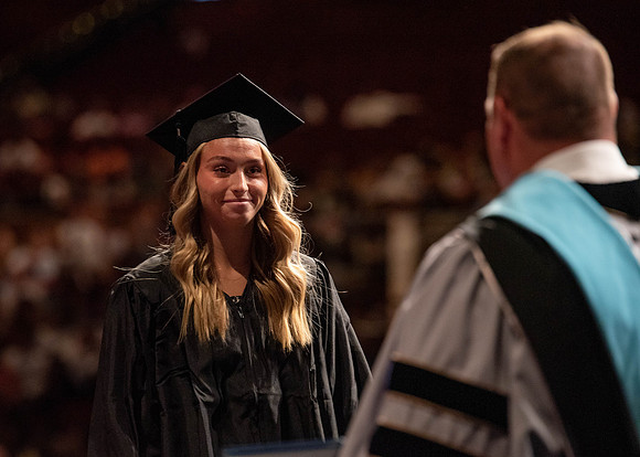 Students partipate in walking to graduate from the College of Business and Communication.