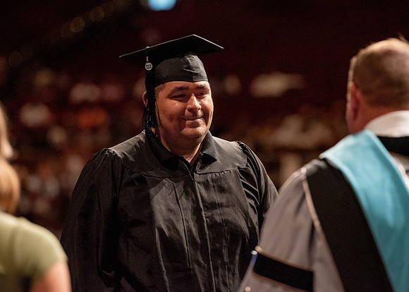 Students partipate in walking to graduate from the College of Business and Communication.
