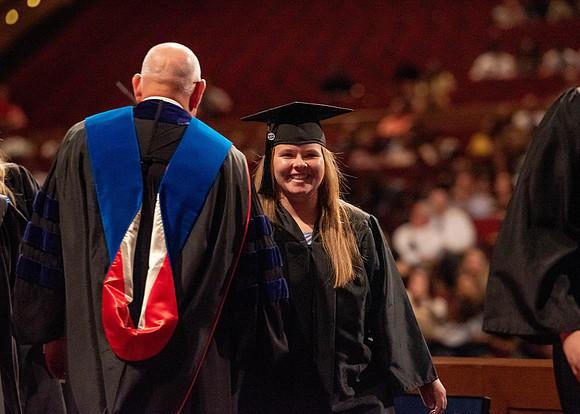 Students partipate in walking to graduate from the College of Business and Communication.