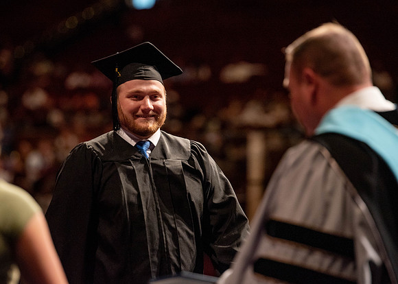 Students partipate in walking to graduate from the College of Business and Communication.