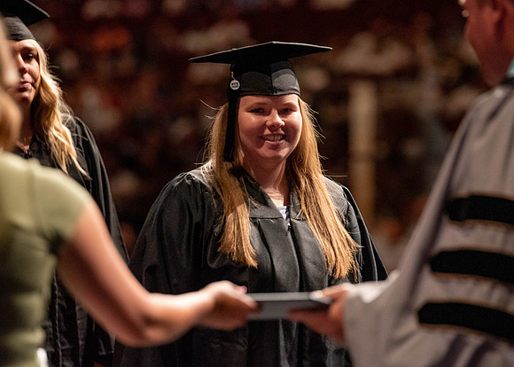 Students partipate in walking to graduate from the College of Business and Communication.