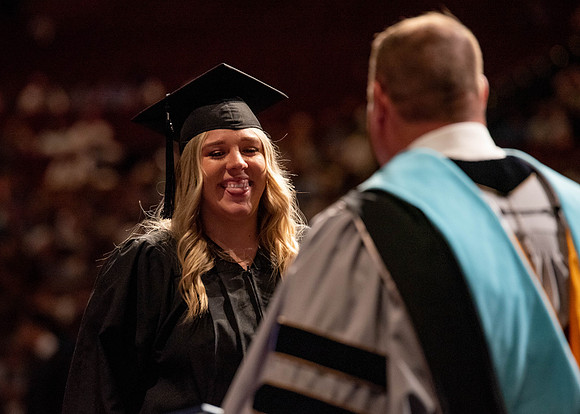 Students partipate in walking to graduate from the College of Business and Communication.