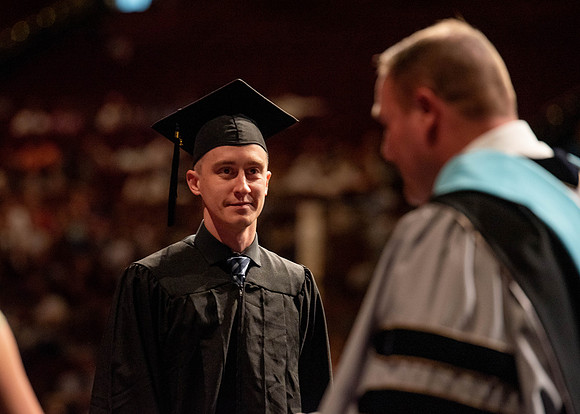 Students partipate in walking to graduate from the College of Business and Communication.