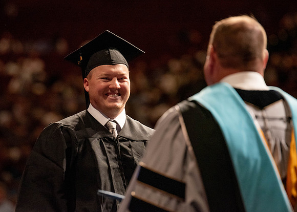 Students partipate in walking to graduate from the College of Business and Communication.