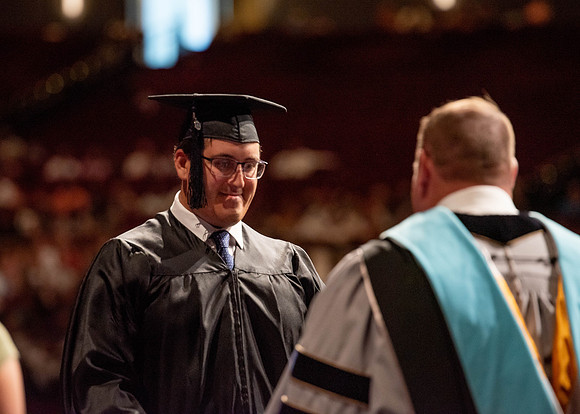 Students partipate in walking to graduate from the College of Business and Communication.
