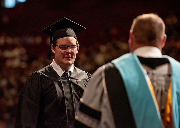 Students partipate in walking to graduate from the College of Business and Communication.