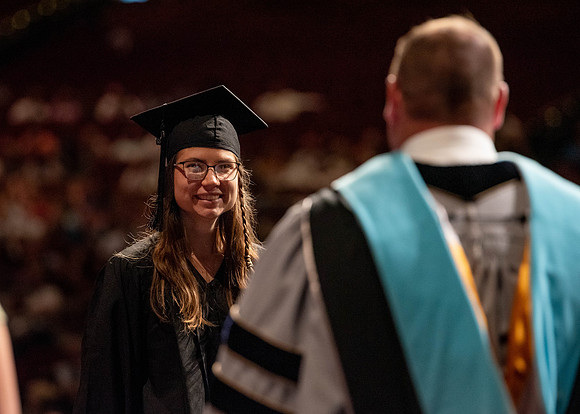Students partipate in walking to graduate from the College of Business and Communication.