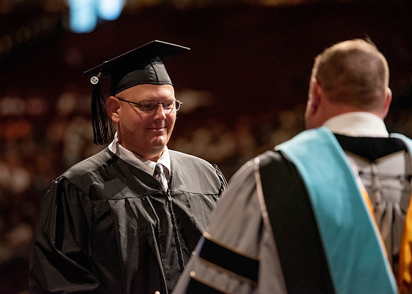 Students partipate in walking to graduate from the College of Business and Communication.