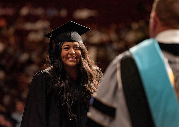 Students partipate in walking to graduate from the College of Business and Communication.