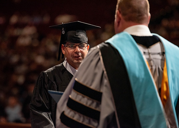 Students partipate in walking to graduate from the College of Business and Communication.